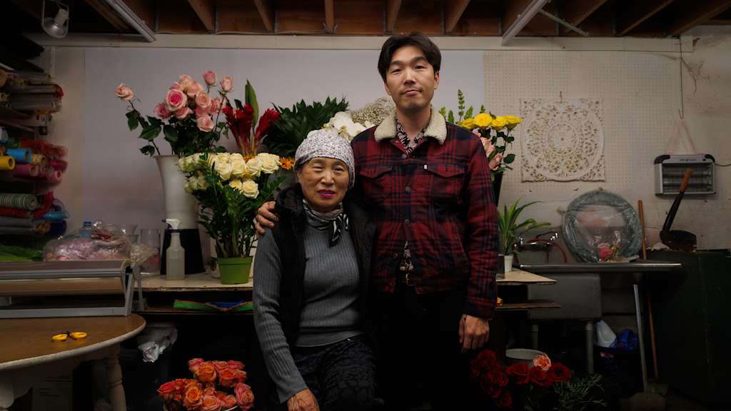 Ein Mann und eine Frau stehen Arm in Arm in einem Blumenladen