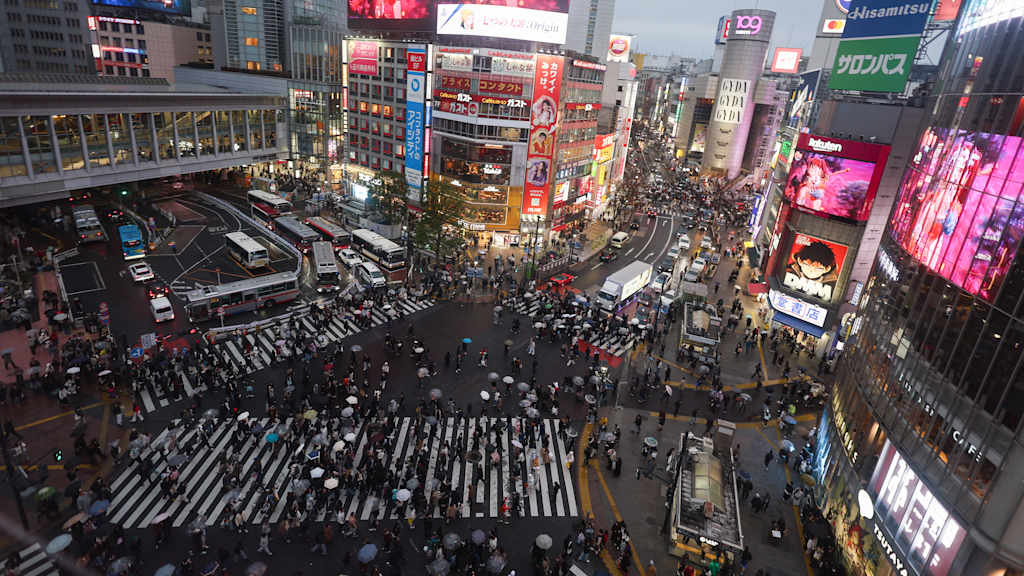 Die Shibuya Kreuzung in Tokio mit einer großen Masse an Leuten, die die Straße überqueren.