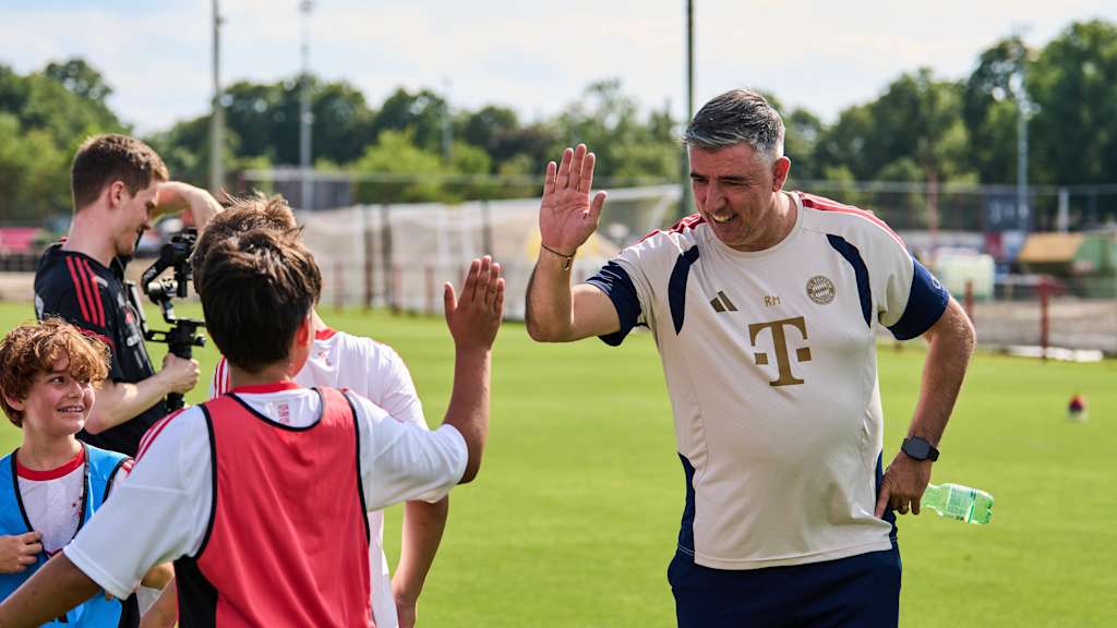 Roy Makaay choca las palmas con un niño durante un entrenamiento.
