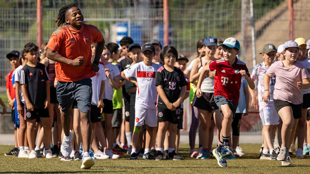 Wisdom Mike joggt mit Grundschülern beim Jugend trainiert-Programm des FC Bayern an der Säbener Straße