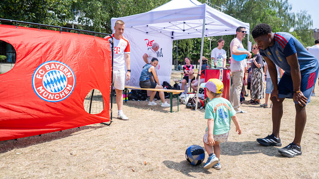 Allan Bohomo vom FC Bayern hilft einem Kind beim Torwandschießen beim PIN. Kindertag 2026