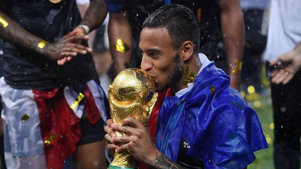 Corentin Tolisso, eingewickelt in die französische Fahne, küsst den WM-Pokal
