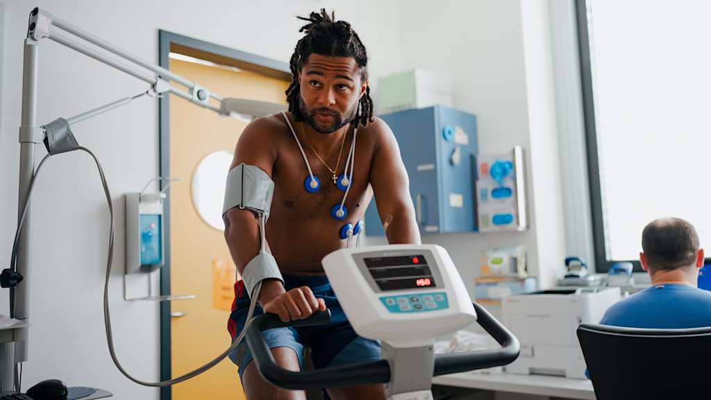 Serge Gnabry sitzt verkabelt auf einem Fahrradergometer bei der sportmedizinischen Untersuchung