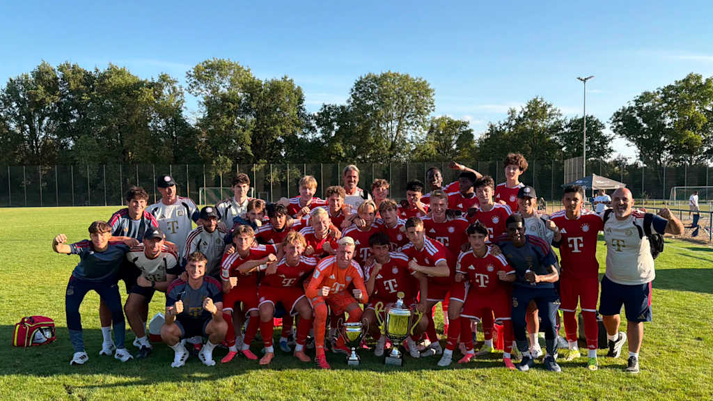 Die U17 des FC Bayern feiert ihren Pokalsieg auf einem Mannschaftsfoto mit zwei Pokalen zu ihren Füßen.