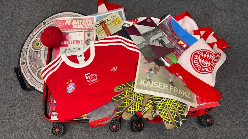 Ein Koffer, auf dem viele Bayern-Utensilien liegen: Trikots, Zeitungen, Tickets