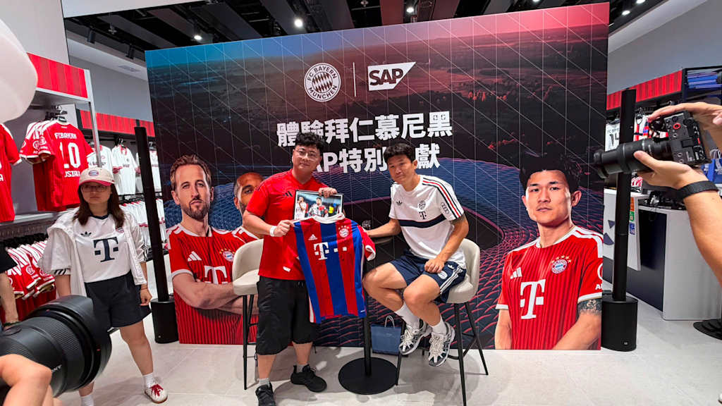 Minjae Kim und ein Fan halten ein FC Bayern Trikot bei einer SAP-Veranstaltung