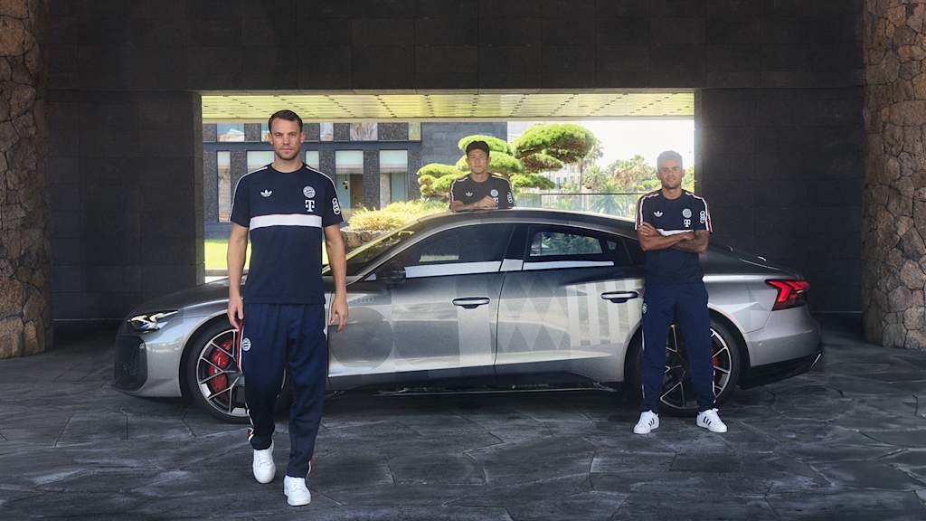 Manuel Neuer, Minjae Kim und Luis Diaz stehen vor einem Audi