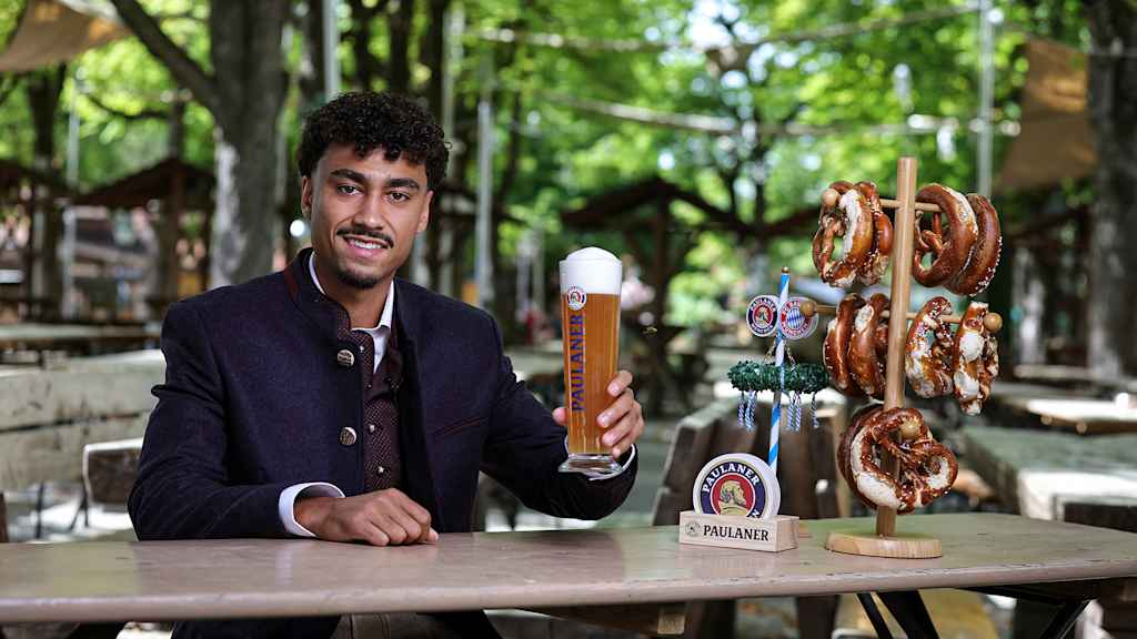 Nathaniel Brown, con traje tradicional bávaro, sentado en un Biergarten y con una cerveza Paulaner en la mano.