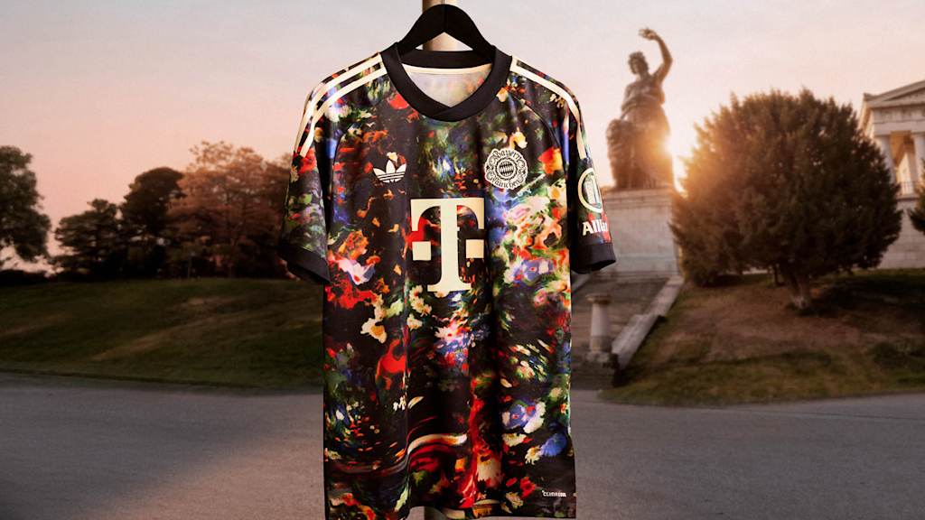Das neue FC Bayern-Wiesn-Trikot 2026/27 mit farbenfrohem floralen Muster hängt vor der Bavaria auf der Theresienwiese