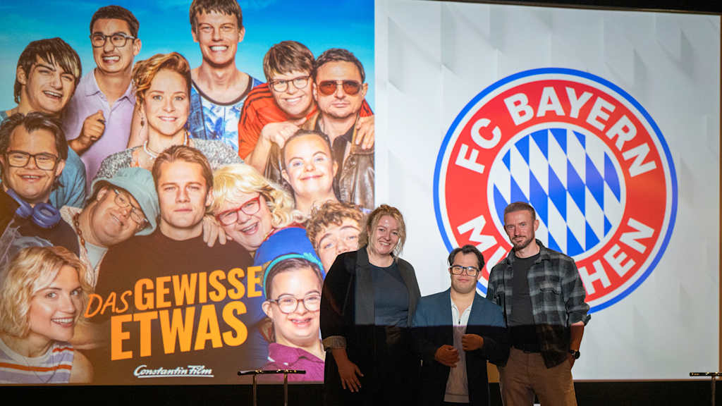 Cast und Produzenten des Films das Gewisse Etwas vor einer Kinoleinwand