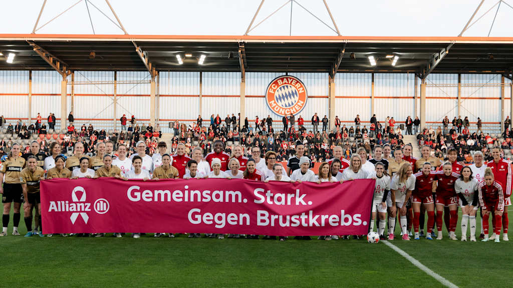 Die beiden Teams vor der Veröffentlichung gemeinsam mit einem Banner der Allianz für den Kampf gegen Brustkrebs.