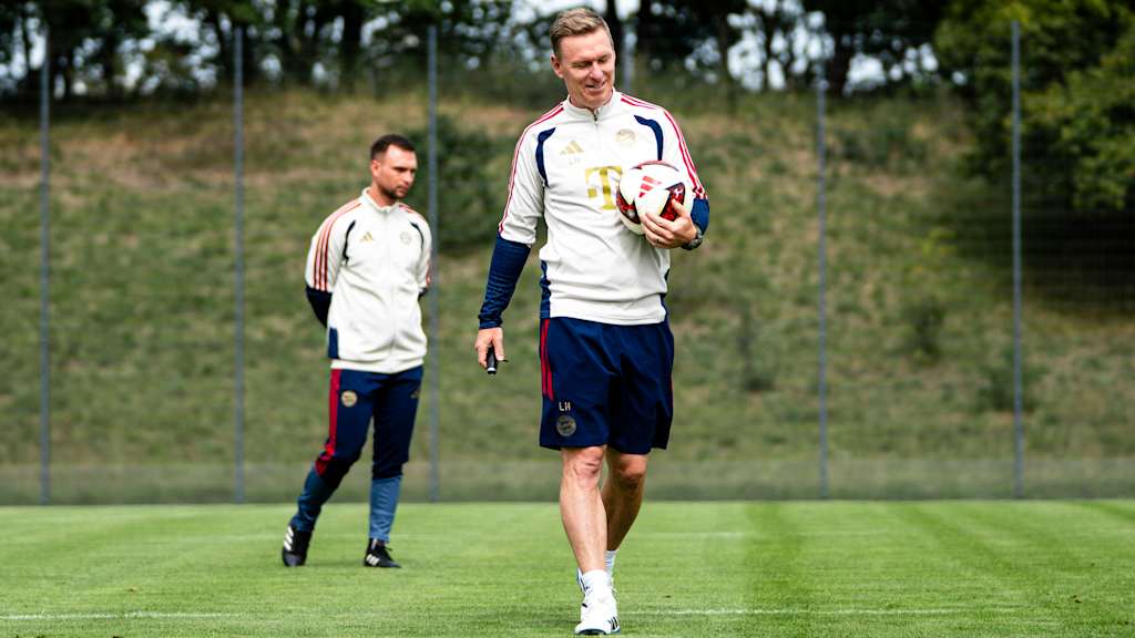 Der Trainer lacht mit dem Ball in der Hand.