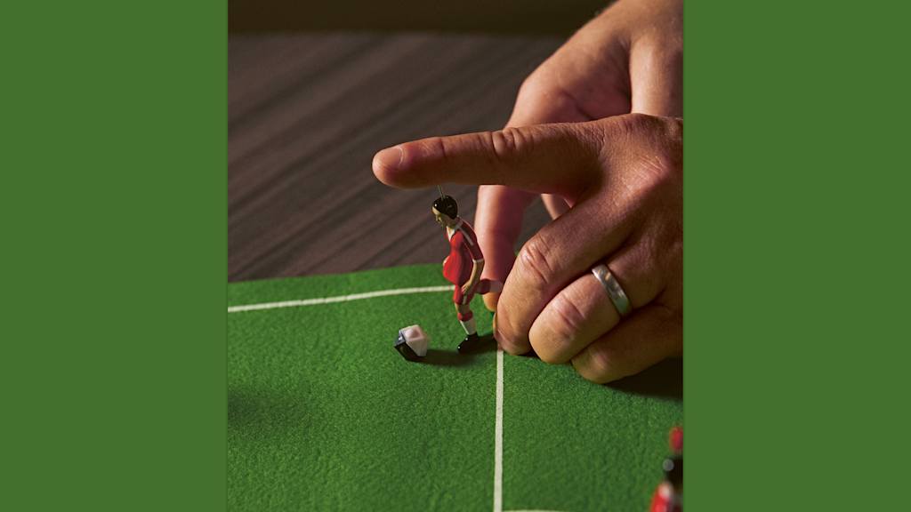 Eine Hand führt einen Spielzug beim Tipp Kick aus