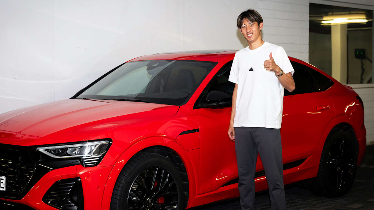 Hiroki Ito, Neuzugang des FC Bayern, steht vor einem roten Audi