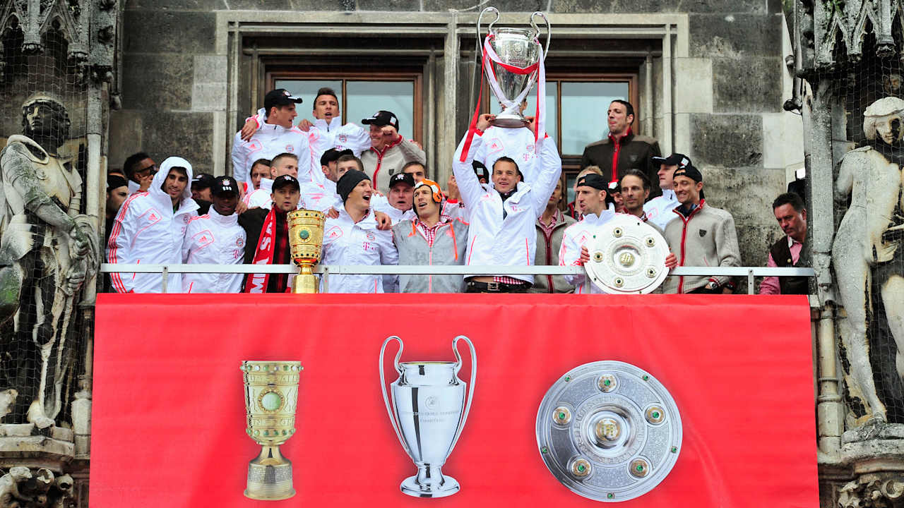 Die Spieler des FC Bayern feiern mit der Meisterschale, dem DFB-Pokal und dem Champions League-Pokal auf dem Rathausbalkon am Marienplatz