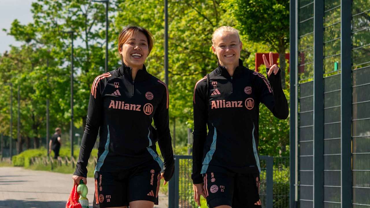 Momoko Tanikawa und Pernille Harder laufen lächelnd zum Trainingsplatz und zeigen ein Peace-Zeichen.