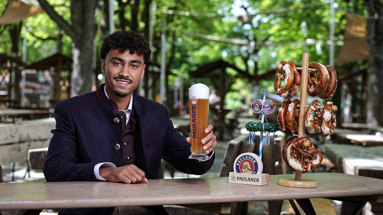 Nathaniel Brown, con traje tradicional bávaro, sentado en un Biergarten y con una cerveza Paulaner en la mano.