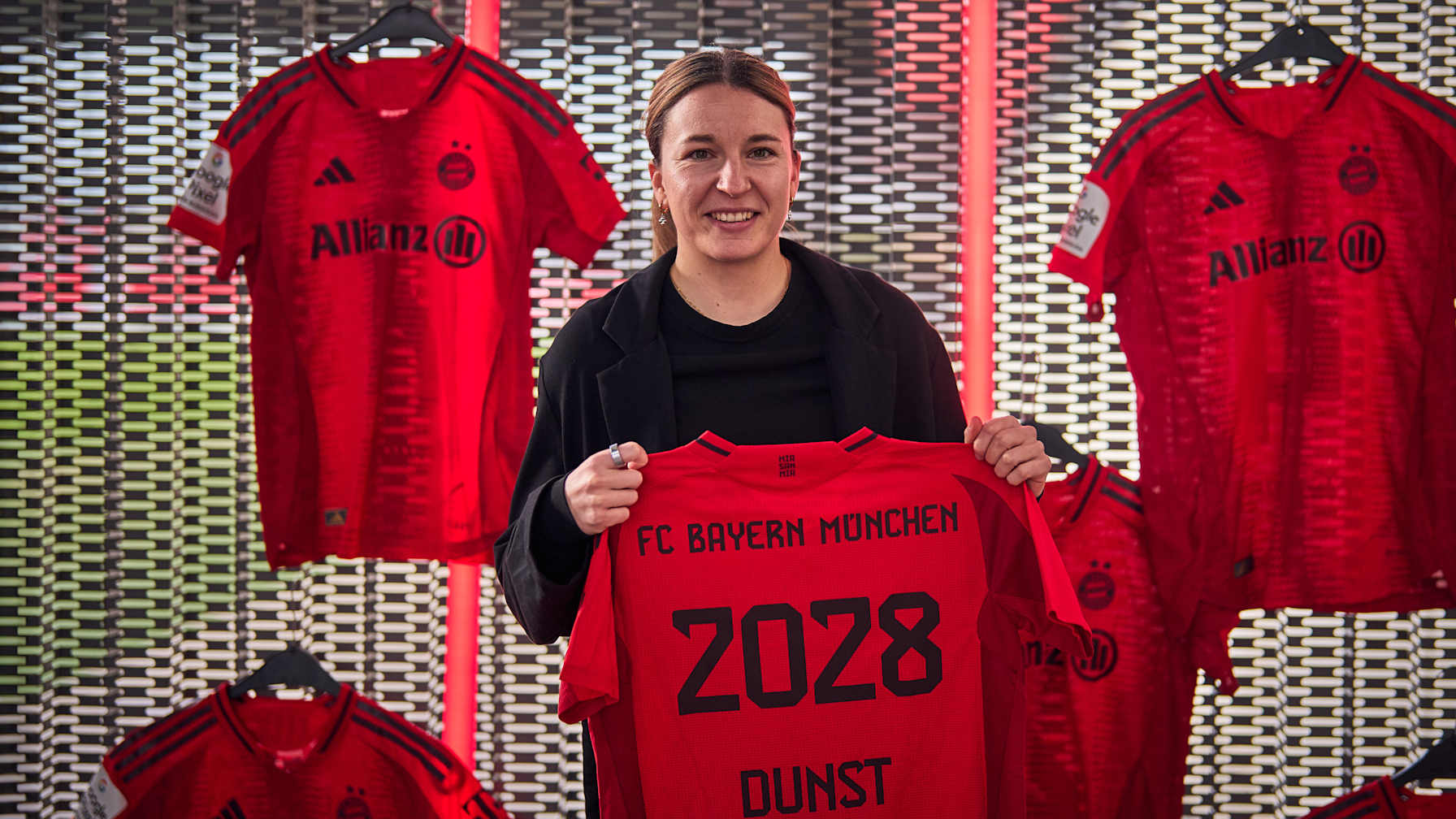 Barbara Dunst hält stehend das Trikot mit ihrer Vertragslaufzeit in die Höhe.