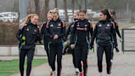 Die Mannschaft läuft sich unterhaltend und lächelnd auf einem Weg zum Trainingsplatz.