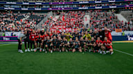 A group photo of the team celebrating in front of the Bayern block.