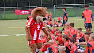 Berni beim Fußballcamp in Berlin; klatscht die Kids ab, die auf dem Boden sitzen