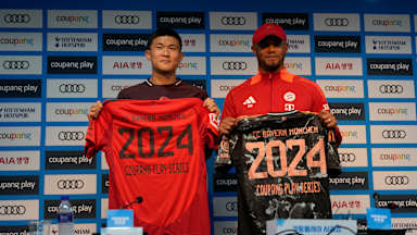 Vincent Kompany und Minjae Kim halten vor dem Testspiel gegen Tottenham in Seoul jeweils ein Trikot hoch