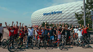 Gruppenbild der Teilnehmer der FC Bayern-Fahrrad Aktion vor der Allianz Arena