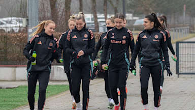 Die Mannschaft läuft sich unterhaltend und lächelnd auf einem Weg zum Trainingsplatz.