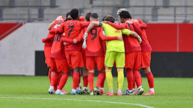 Die U19 des FC Bayern bildet einen Kreis vor dem Spiel.