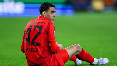 Jamal Musiala sitzt auf dem Boden nachdem er sich im Spiel beim FC Augsburg verletzt hat