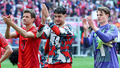 Thomas Müller, Aleks Pavlovic und Jonas Urbig klatschen in Richtung der Fans.