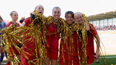 Magdalena Eriksson, Linda Sembrant, Momoko Tanikawa und Pernille Harder von den FC Bayern Frauen stehen Arm in Arm mit Lametta um den Hals auf dem Platz und lächeln in die Kamera.