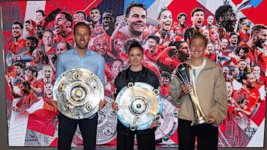Harry Kane, Sarah Zadrazil und Caro Simon präsentieren die Trophäen für die Titelgewinne 2025.