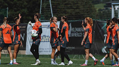 Die Spielerinnen der FC Bayern Frauen klatschen sich auf dem Trainingsplatz ab.