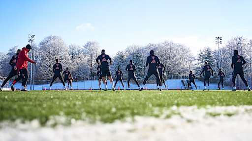 Spieler des FC Bayern laufen sich auf dem Trainingsplatz warm