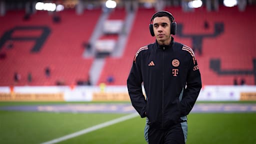 Jamal Musiala mit Kopfhörern auf dem Rasen vor Anpfiff des Bundesliga-Spiels des FC Bayern in Leverkusen.
