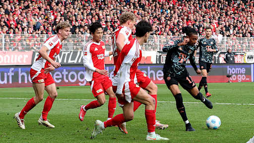 Michael Olise beim Torschuss im Strafraum vor Abwehrspielern von Union Berlin