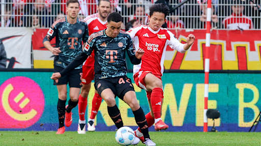 Jamal Musiala (FC Bayern Muenchen) und Woo-yeong Jeong (1. FC Union Berlin) kaempfen um den Ball