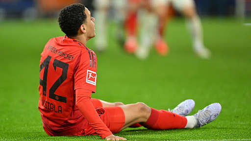 Jamal Musiala sitzt verletzt auf dem Boden im Spiel gegen Augsburg