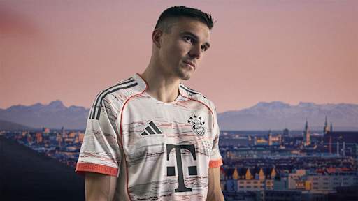 Joao Palhinha im neuen Auswärtstrikot des FC Bayern für die Saison 2025/26 in Weiß, Grau und leuchtendem Coral.