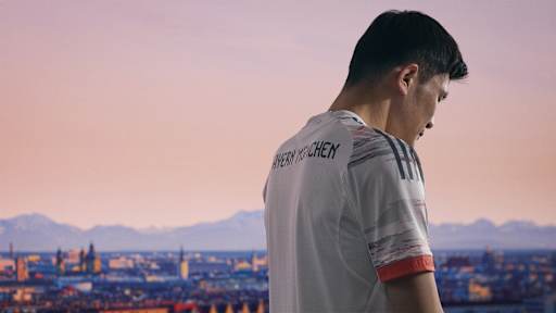 Minjae Kim im neuen Auswärtstrikot des FC Bayern für die Saison 2025/26 in Weiß, Grau und leuchtendem Coral.