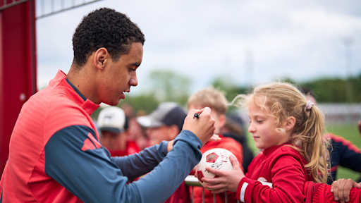 Jamal Musiala gibt einem jungen Fan ein Autogramm im öffentlichen Training des FC Bayern.