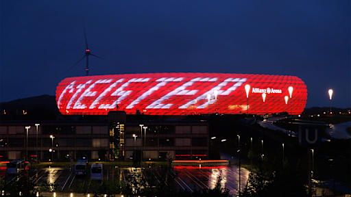 Allianz Arena leuchtet bei Nacht in Rot mit weißem Schriftzug Meister