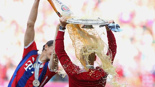Pep Guardiola hält sich die Meisterschale über den Kopf, während Daniel van Buyten ihn mit Bier überschüttet.