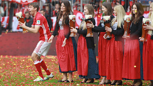 Thomas Müller mit einem Weißbierglas neben Paulaer-Hostessen.