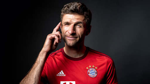 Thomas Müller zwinkert und zeigt sich mit dem Finger an den Kopf