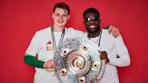 Jonas Urbig und Alphonso Davies vom FC Bayern jubeln mit der Meisterschale.