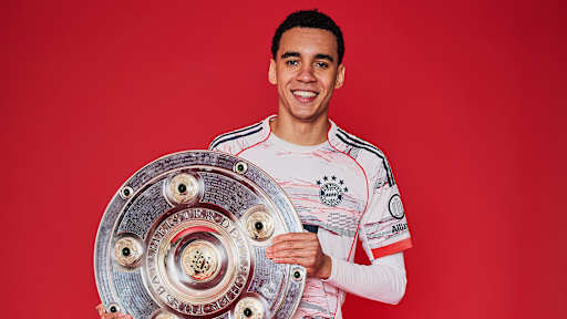 Jamal Musiala vom FC Bayern jubelt mit der Meisterschale.