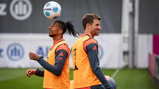 Michael Olise jongliert einen Kopf auf dem Ball, daneben Thomas Müller im FC Bayern-Training vor Bundesliga-Spiel bei TSG Hoffenheim.
