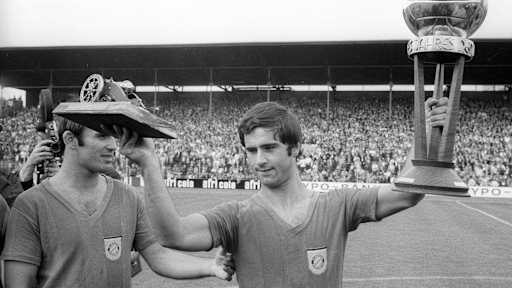 Gerd Müller hebt mehrere Trophäen in die Luft.